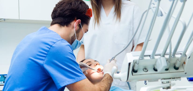 Dentista atendiendo a una paciente en el sillón dental